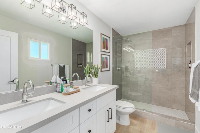 bathroom with vanity, wood-type flooring, toilet, and a tile shower