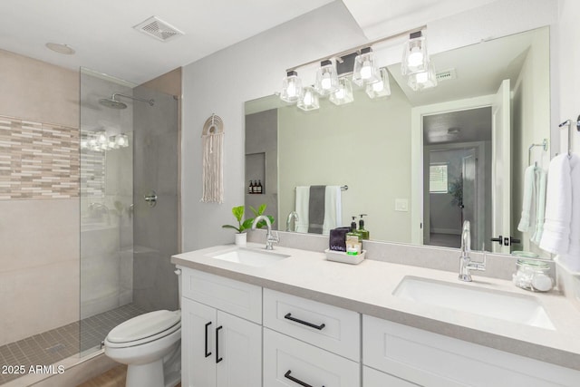 bathroom with vanity, a tile shower, and toilet