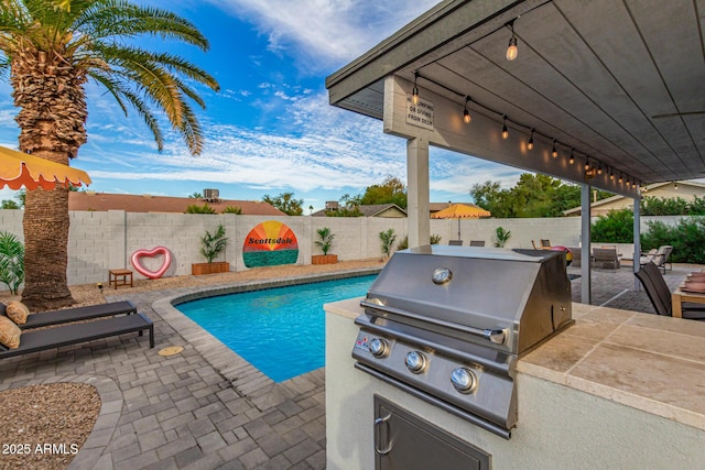 view of pool with a grill, a patio, and an outdoor kitchen