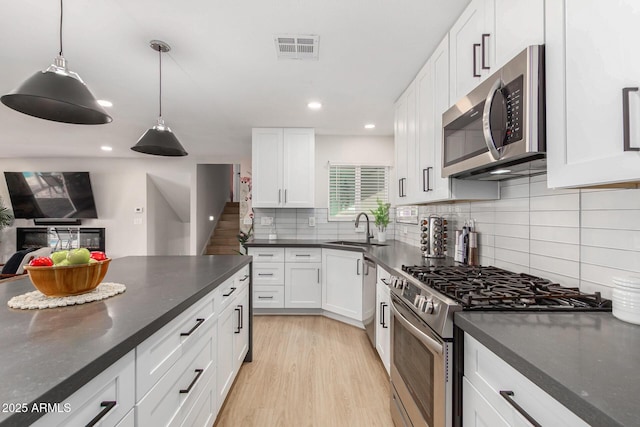 kitchen with appliances with stainless steel finishes, decorative light fixtures, sink, and white cabinets