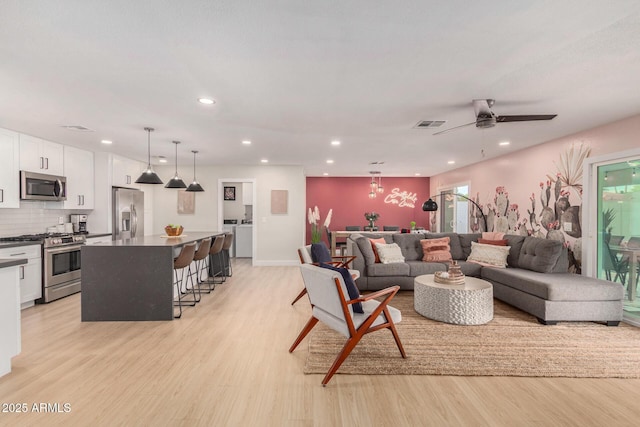 living room with a healthy amount of sunlight, ceiling fan, and light hardwood / wood-style flooring