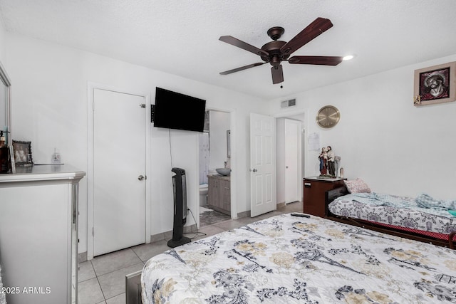 bedroom featuring visible vents, a ceiling fan, ensuite bath, and light tile patterned flooring