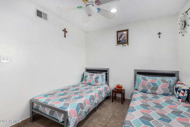 tiled bedroom featuring baseboards, ceiling fan, a textured ceiling, and visible vents
