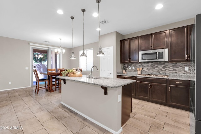 kitchen featuring visible vents, a sink, dark brown cabinetry, appliances with stainless steel finishes, and tasteful backsplash