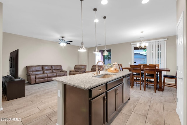 kitchen featuring light stone countertops, a sink, pendant lighting, dishwasher, and ceiling fan with notable chandelier