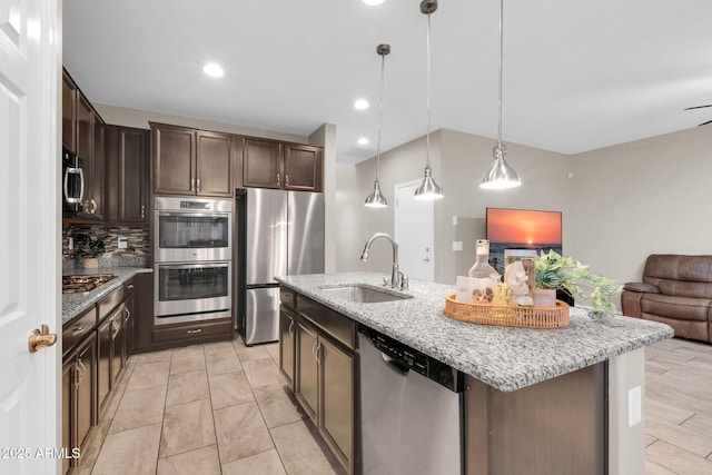 kitchen with a sink, open floor plan, stainless steel appliances, dark brown cabinetry, and decorative backsplash