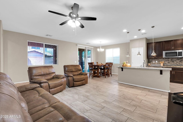 living area with recessed lighting, visible vents, baseboards, and ceiling fan with notable chandelier