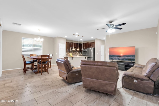 living room featuring recessed lighting, visible vents, ceiling fan with notable chandelier, and baseboards