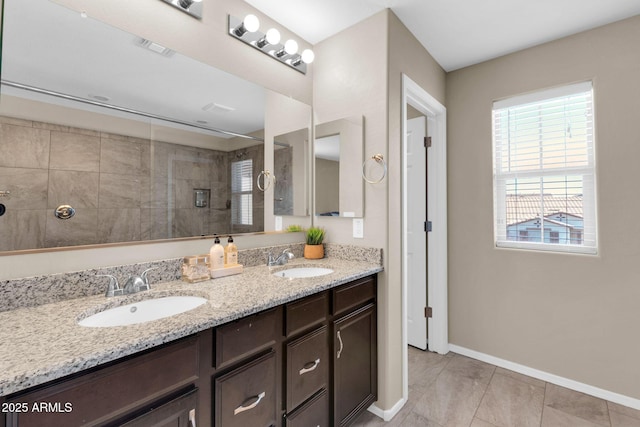 bathroom featuring double vanity, walk in shower, baseboards, and a sink