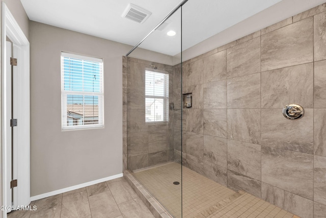 bathroom featuring a tile shower, visible vents, and baseboards