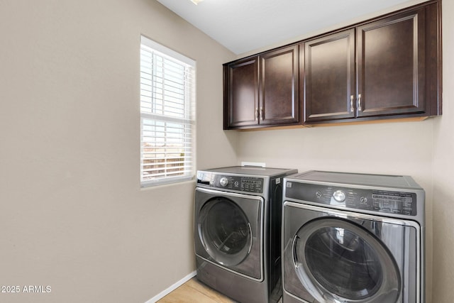 clothes washing area featuring separate washer and dryer, light tile patterned flooring, cabinet space, and baseboards