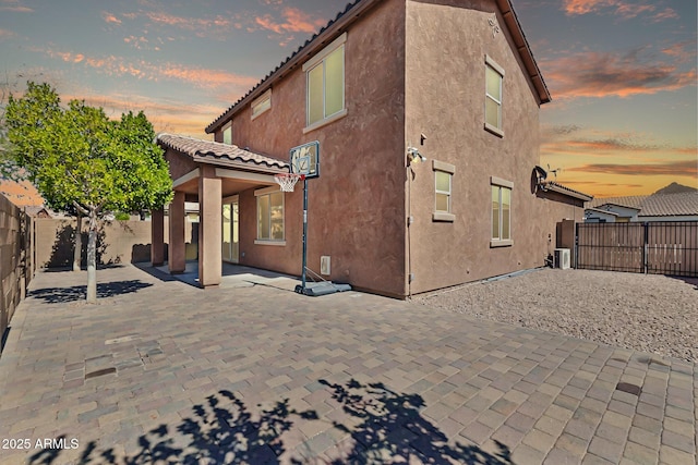 back of house with a tiled roof, a patio area, a fenced backyard, and stucco siding