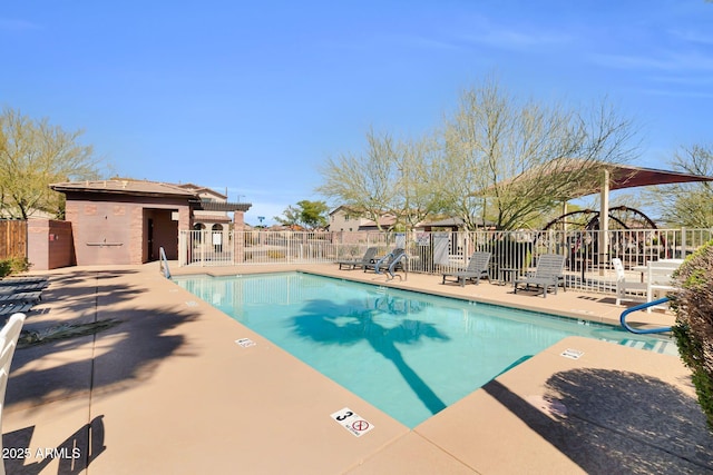 community pool with a patio area and fence