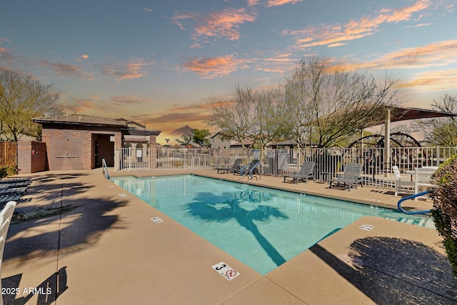 pool at dusk featuring a patio, a community pool, and fence