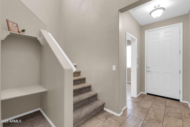 foyer entrance with light tile patterned flooring, visible vents, stairway, and baseboards