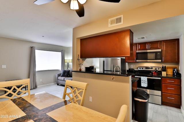 12123 W Bell Rd Unit 218, Surprise, AZ 85378 - kitchen featuring visible vents, a ceiling fan, dark countertops, stainless steel appliances, and a breakfast bar area