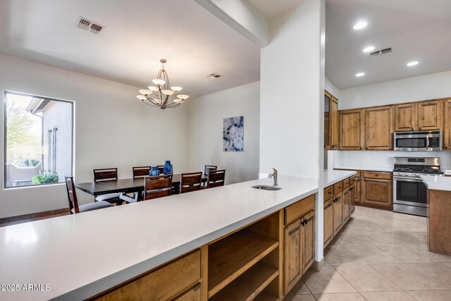 kitchen with stainless steel appliances, visible vents, light countertops, brown cabinetry, and pendant lighting