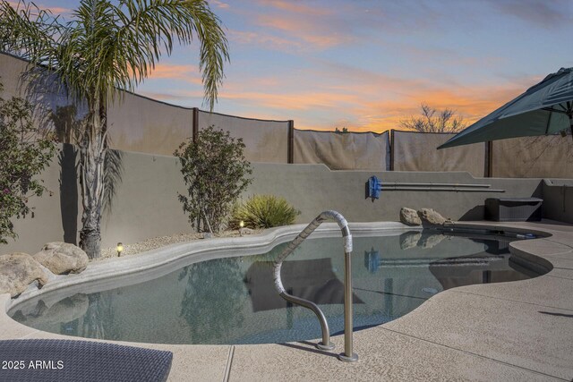 pool at dusk with a fenced backyard and a fenced in pool