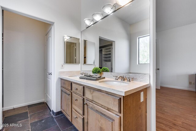 full bath featuring double vanity, baseboards, and a sink