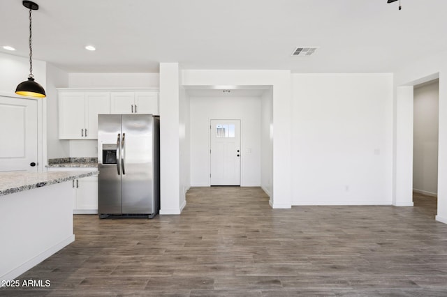 kitchen featuring stainless steel refrigerator with ice dispenser, decorative light fixtures, white cabinets, and light stone countertops