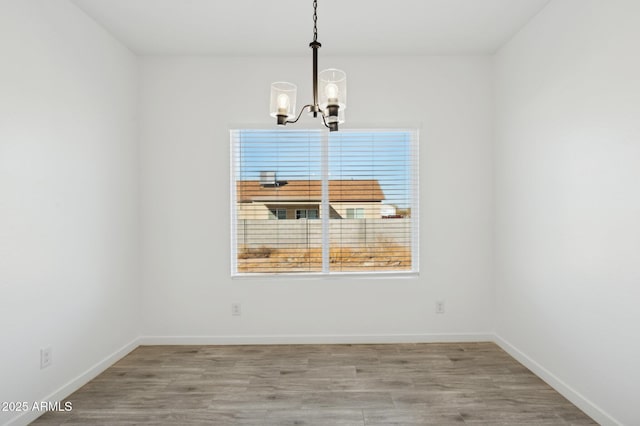 spare room featuring a notable chandelier and hardwood / wood-style flooring