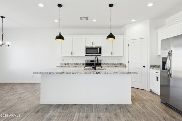 kitchen with white cabinetry, pendant lighting, appliances with stainless steel finishes, and an island with sink