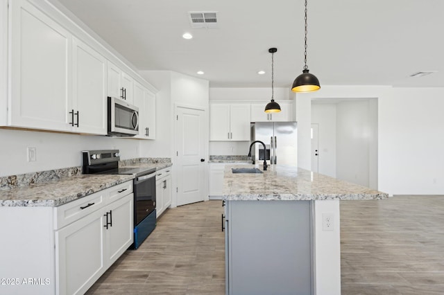 kitchen featuring white cabinetry, stainless steel appliances, sink, hanging light fixtures, and a center island with sink