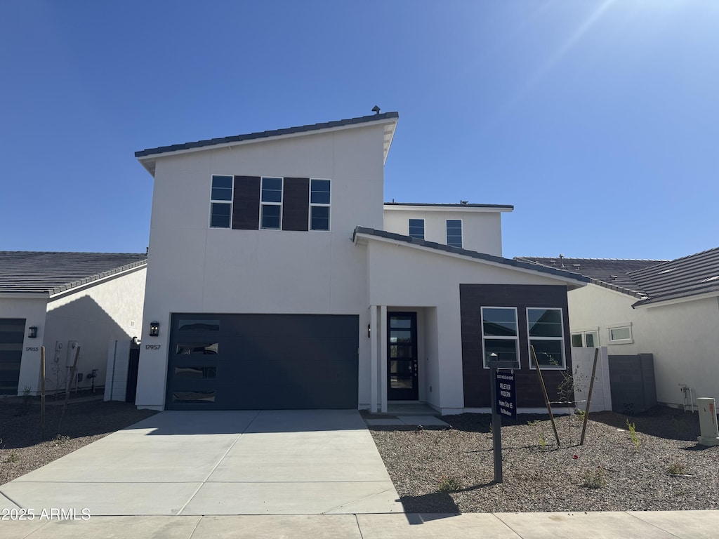 contemporary house featuring concrete driveway, an attached garage, and stucco siding