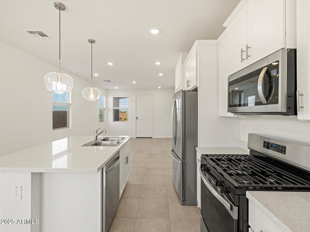 kitchen featuring sink, decorative light fixtures, appliances with stainless steel finishes, a kitchen island with sink, and white cabinets