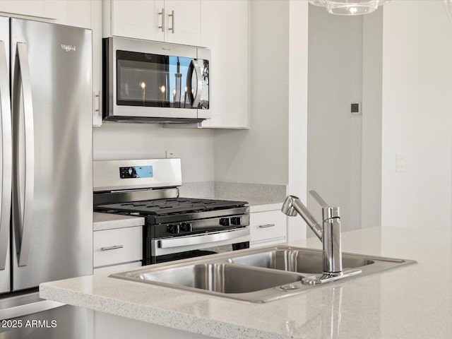 kitchen featuring light stone counters, appliances with stainless steel finishes, sink, and white cabinets