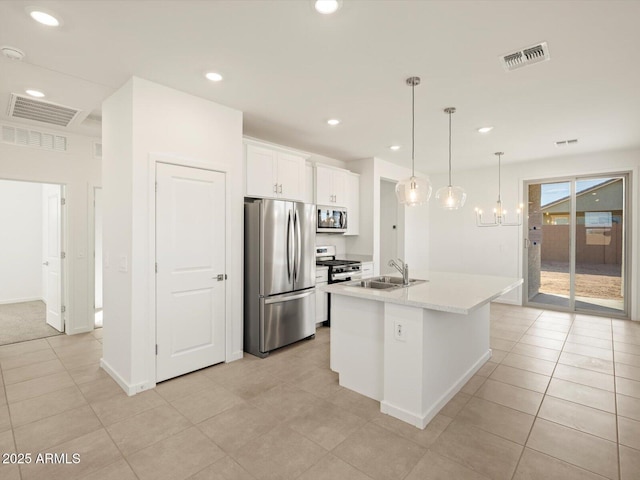 kitchen featuring appliances with stainless steel finishes, pendant lighting, an island with sink, sink, and white cabinets