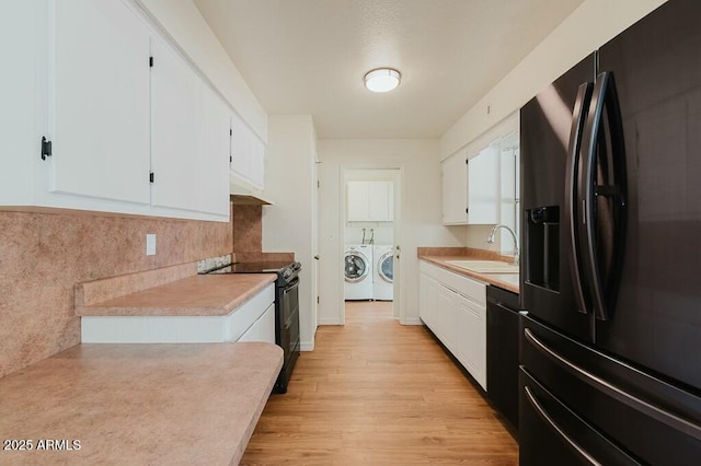 kitchen with white cabinetry, sink, refrigerator with ice dispenser, range with two ovens, and washing machine and clothes dryer