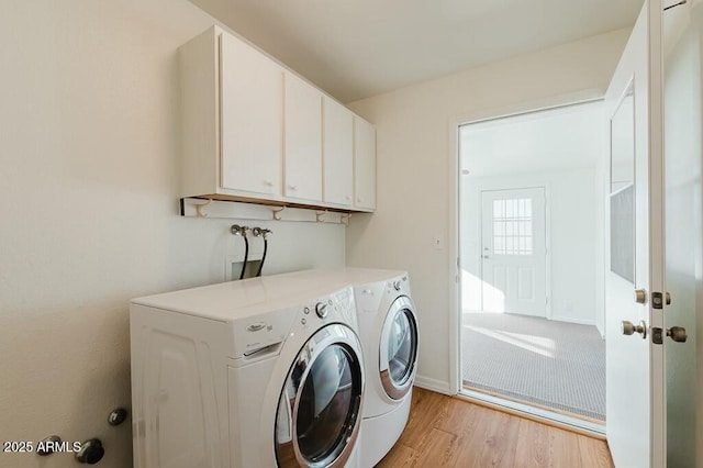 washroom featuring light hardwood / wood-style flooring, washing machine and dryer, and cabinets