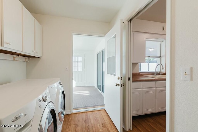 laundry room featuring cabinets, light hardwood / wood-style floors, sink, and washer and dryer