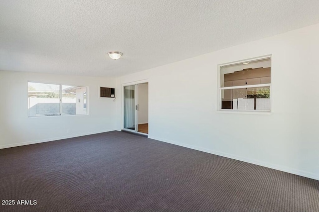 carpeted spare room with an AC wall unit and a textured ceiling