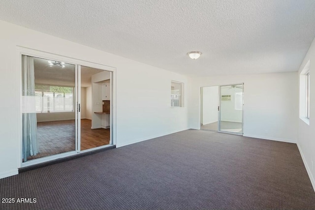 empty room with dark carpet and a textured ceiling