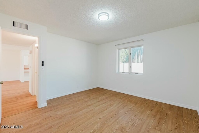 empty room with light hardwood / wood-style flooring and a textured ceiling