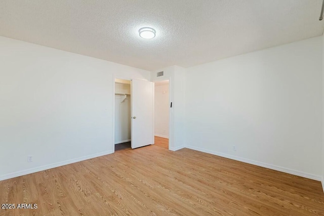 empty room with light hardwood / wood-style flooring and a textured ceiling