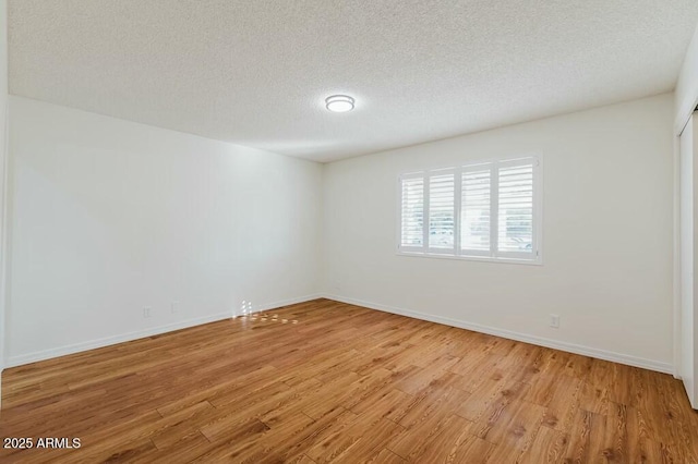 unfurnished room with light hardwood / wood-style flooring and a textured ceiling