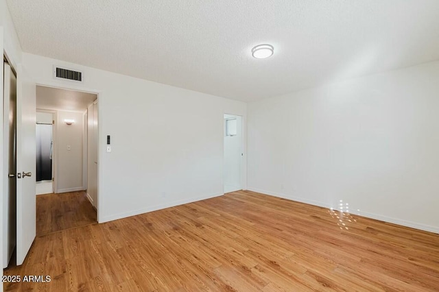 spare room with light hardwood / wood-style floors and a textured ceiling