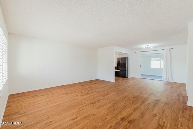 unfurnished living room featuring light hardwood / wood-style flooring and a textured ceiling