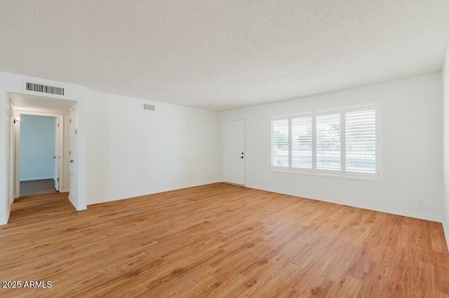 spare room featuring light hardwood / wood-style flooring and a textured ceiling