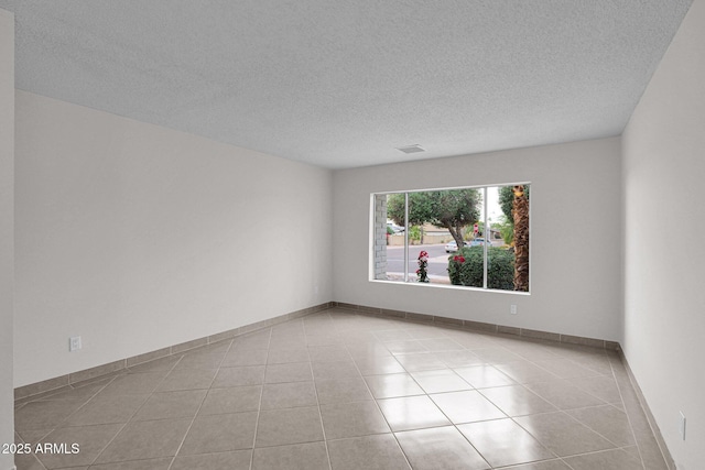 unfurnished room featuring a textured ceiling, baseboards, and tile patterned floors