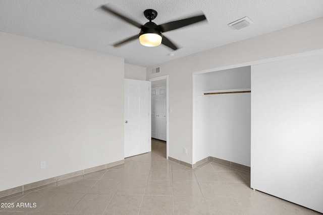 unfurnished bedroom featuring a closet, visible vents, a textured ceiling, and light tile patterned floors