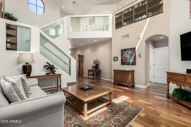 7955 E Chaparral Rd Unit 17, Scottsdale, AZ 85250 - living area featuring arched walkways, a towering ceiling, wood finished floors, and stairs
