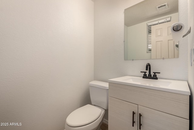 half bath featuring toilet, vanity, and visible vents