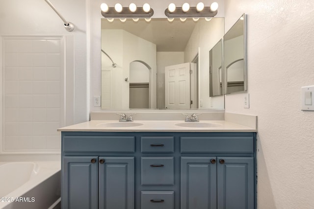 bathroom with a sink, double vanity, and a textured wall