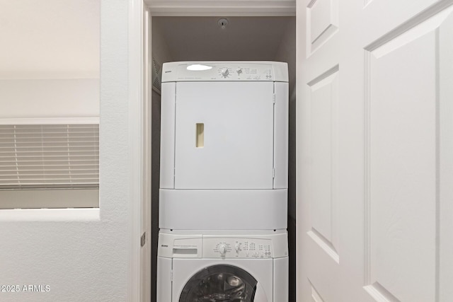 clothes washing area featuring stacked washing maching and dryer and laundry area