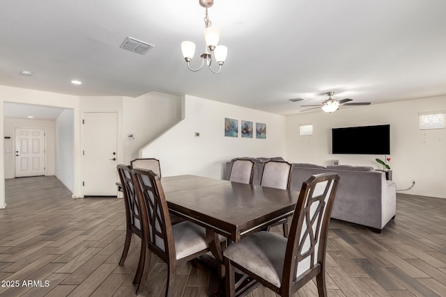 dining space featuring wood finished floors, ceiling fan with notable chandelier, and visible vents