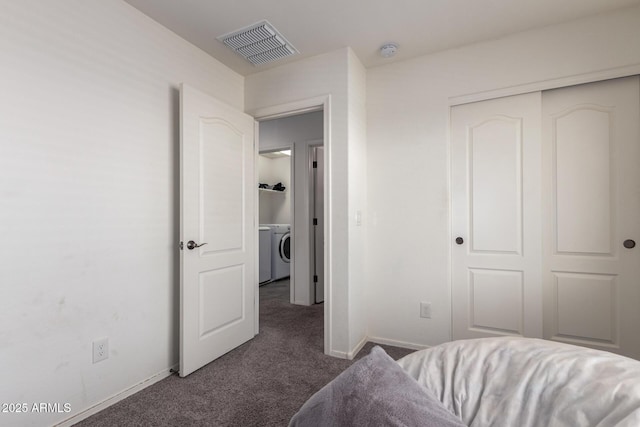 bedroom featuring visible vents, baseboards, a closet, dark colored carpet, and washer / dryer